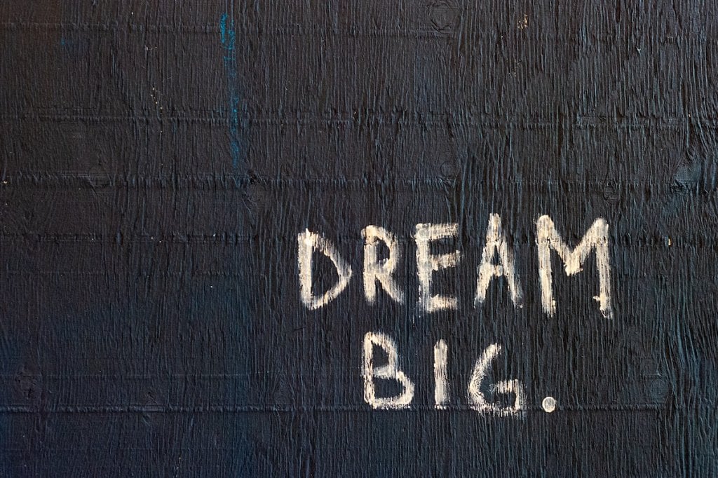 Graffiti on a wall that reads: Dream big.