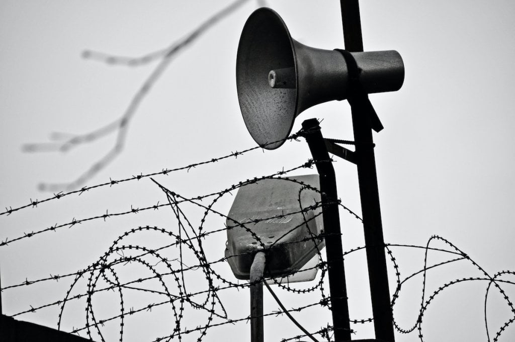 Barbed wire and loudspeakers on the edge of a prison.