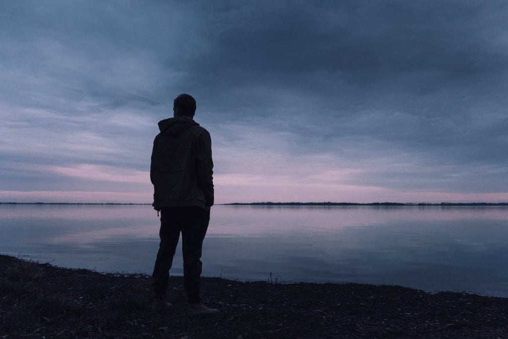 Silhouette of a man looking over a dusk horizon