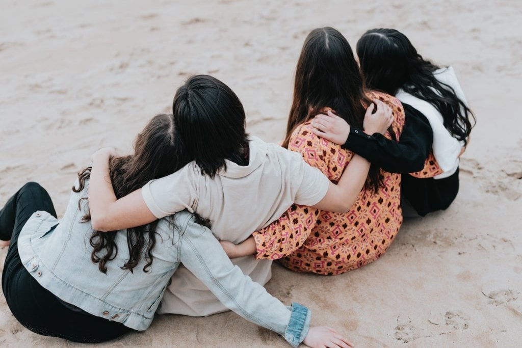 Four friends, hugging on the beach