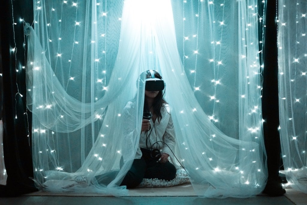 A woman wearing a VR headset under an LED lace curtain