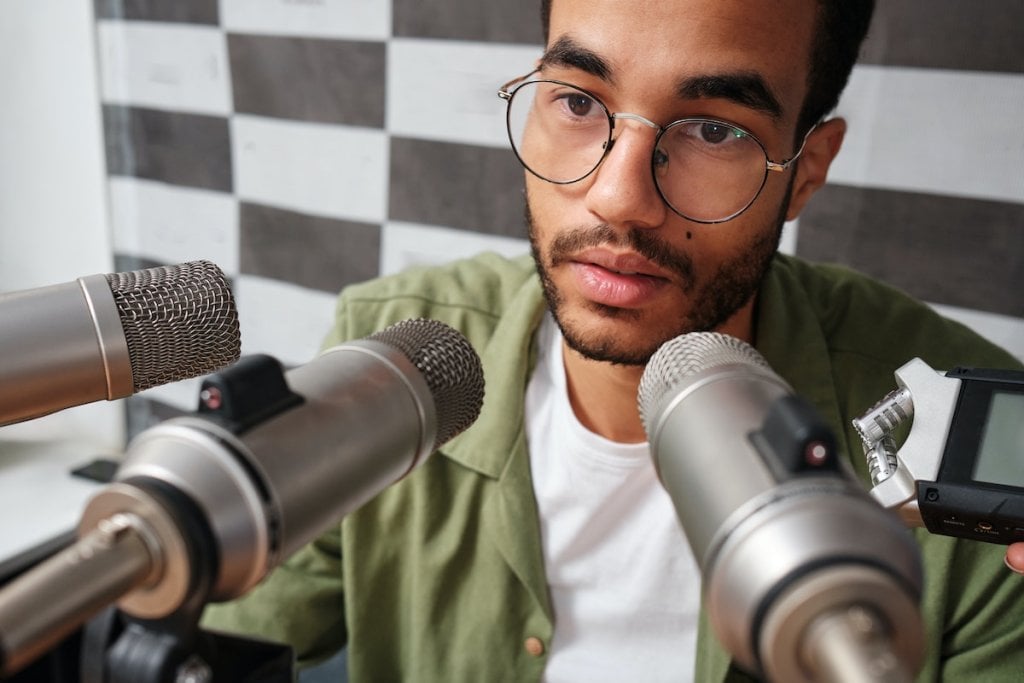 A man speaking into a number of microphones.