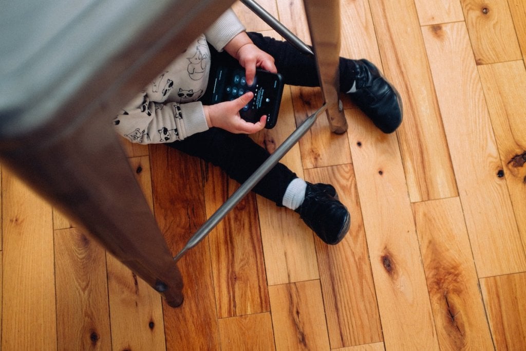 A toddler using an iPhone on the floor