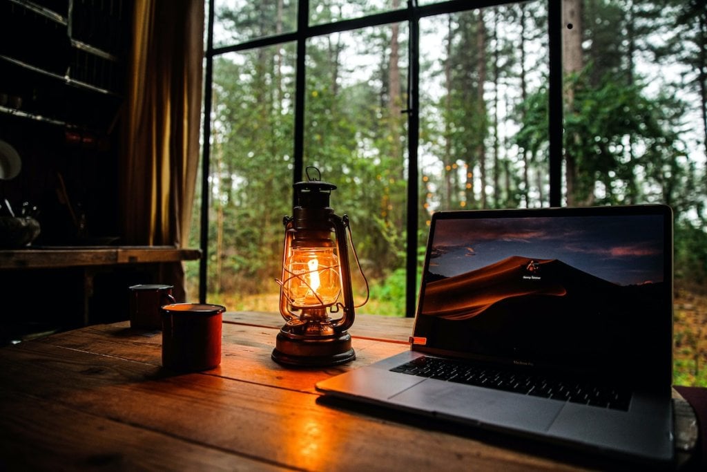 A laptop open on a table in a cabin in the woods
