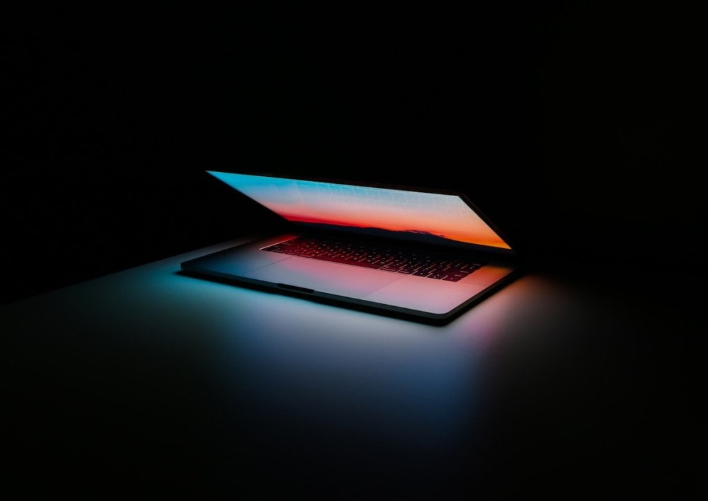 An abstract image of a semi-closed laptop in a dark room