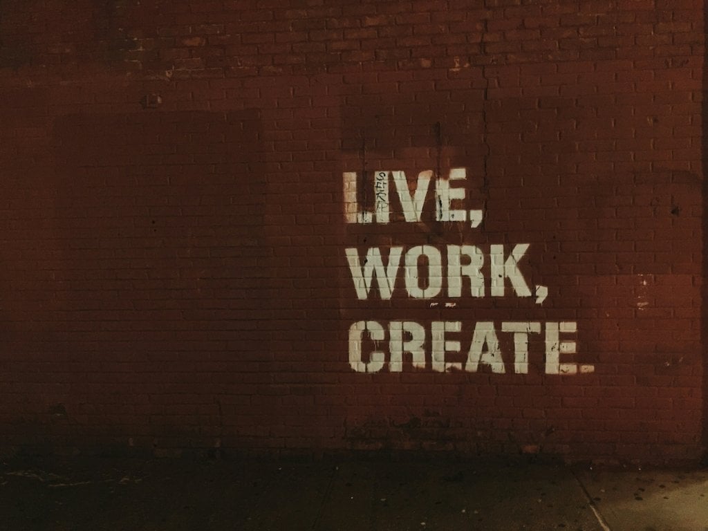 Stenciled letters on a wall: Live, Work, Create.
