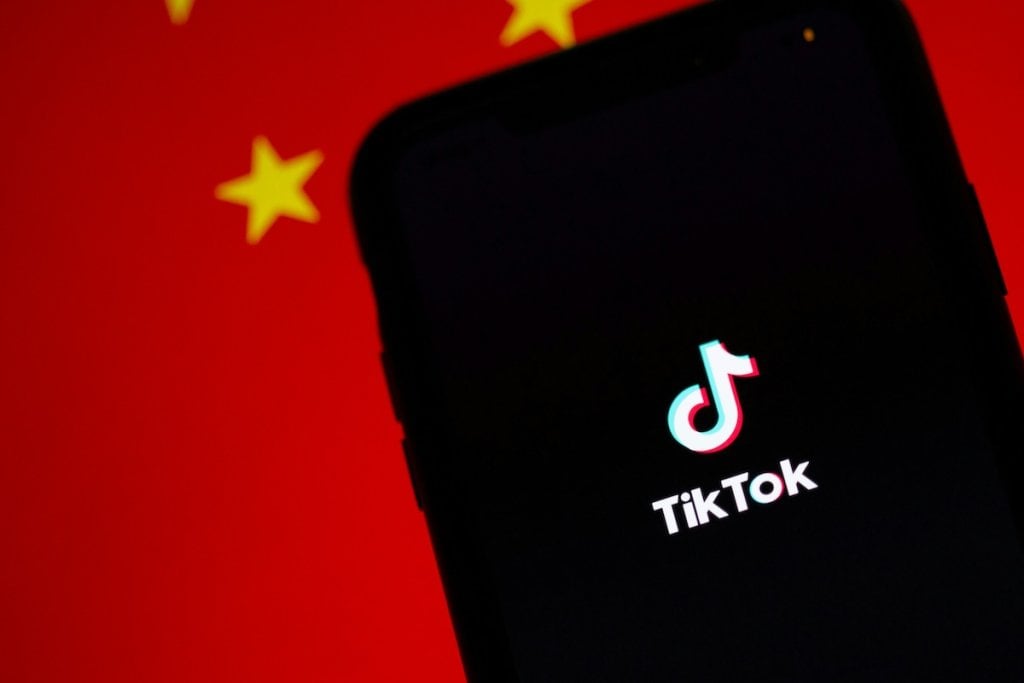 A phone showing TikTok with the Chinese flag in the background