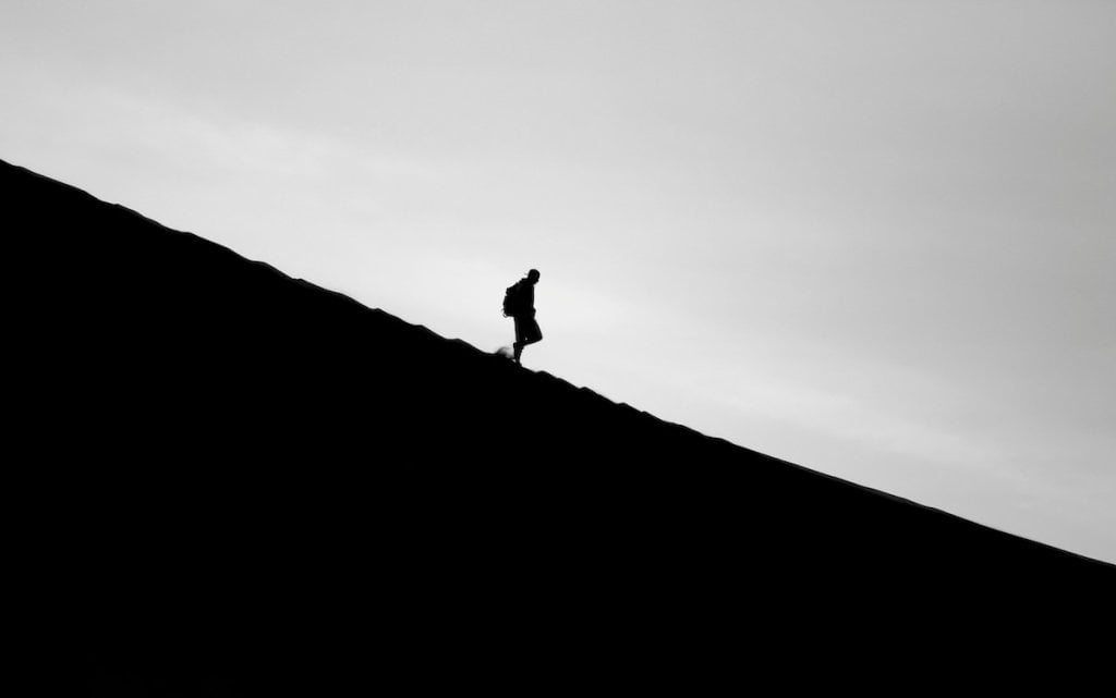 The silhouette of a man walking downhill