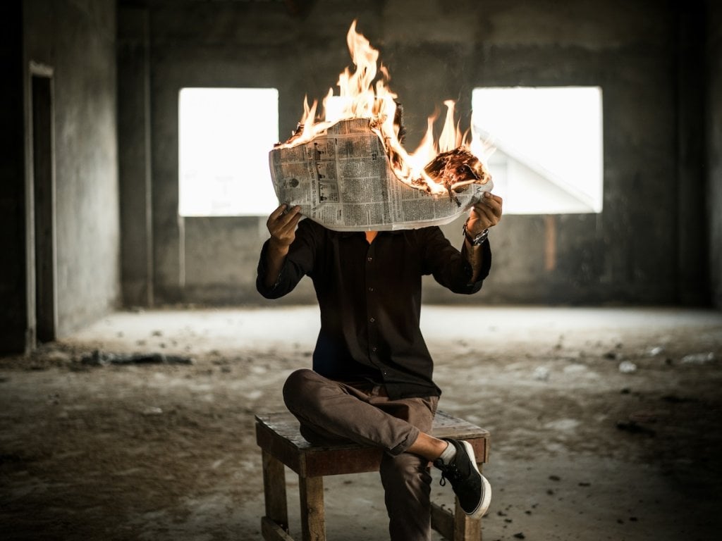 A man holding a burning newspaper